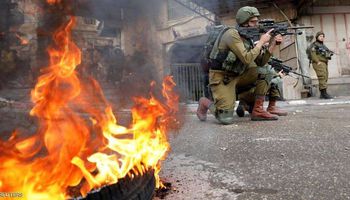جندي إسرائيلي يصوب بندقيته على متظاهرين فلسطينيين في الخليل (رويترز)