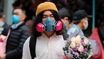 رجل يرتدي قناعا واقيا من كورونا في هونج كونج حاملا باقة زهور (REUTERS)