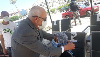 محافظ بورسعيد يساعد سيدة مسنة في ارتداء الكمامة