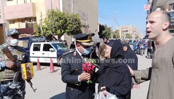 رجال الشرطة يوزوعون الورود على المواطنين في قنا