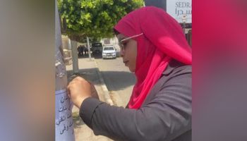 فتاة تعلق لافتات لتوعية الشباب على كورنيش سوهاج