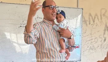 الدكتور وليد عفيفي، عميد كلية التجارة جامعة كفر الشيخ وهو يحمل الصغيرة أثناء شرح المحاضرة 
