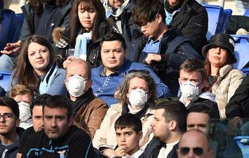 إيطاليون يرتدون كمامات واقية أثناء مشاهدتهم لمباراة كرة قدم (Reuters )