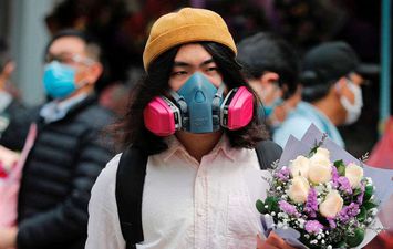 رجل يرتدي قناعا واقيا من كورونا في هونج كونج حاملا باقة زهور (REUTERS)
