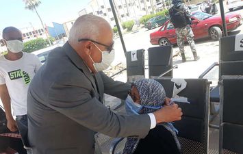 محافظ بورسعيد يساعد سيدة مسنة في ارتداء الكمامة