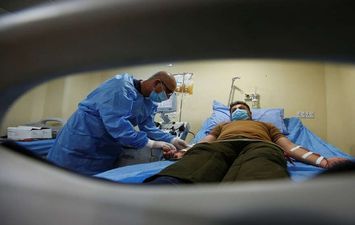 طبيب يُعالج مصاباً بـ كورونا في العراق