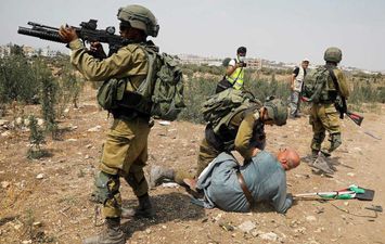 جندي إسرائيلي يجثو على رقبة مسن فلسطيني