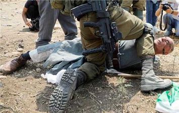 جندي إسرائيلي يجثو على رقبة مسن فلسطيني
