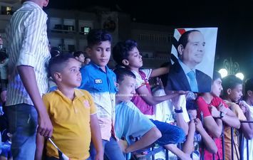 اطفال يحملون صور الرئيس السيسي في احتفالات اكتوبر