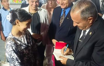 محافظ بورسعيد يهدى طفلة كتاب بتوقيعه