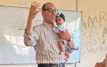 الدكتور وليد عفيفي، عميد كلية التجارة جامعة كفر الشيخ وهو يحمل الصغيرة أثناء شرح المحاضرة 