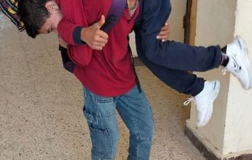 طالب يحمل زميله من ذوى الهمم بسوهاج