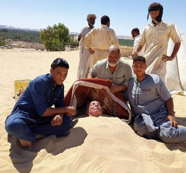 الفنانين يمارسون السياحية العلاجية بالدفن في الرمال بواحة سيوة 