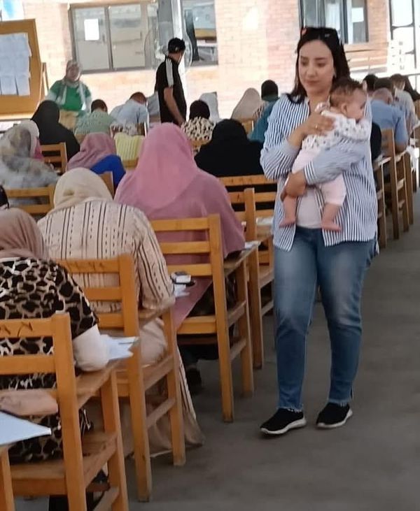 دكتورة جامعية تحمل طفل رضيع والدته تؤدى امتحانها و تتعثر بسبب بكائه فى الكتابة 