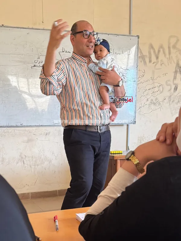 الدكتور وليد عفيفي، عميد كلية التجارة جامعة كفر الشيخ وهو يحمل الصغيرة أثناء شرح المحاضرة 